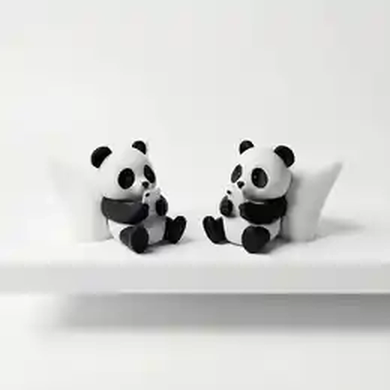Two panda figurines with phones